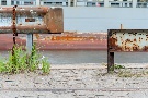Leitplanke an der Kaimauer mit Containerschiff im Hintergrund