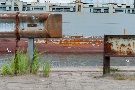 Leitplanke an der Kaimauer mit Containerschiff im Hintergrund